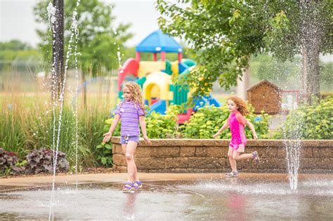 Breathtaking bronze figural water fountain created by polish artist malgorzata chodakowska. Two Girls Playing In Water Fountains At Park Stock Photo ...