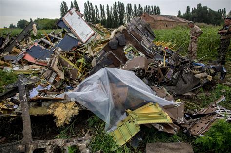 A ukrainian covers a body with a plastic sheet in a field. Vliegtuigongelukken tegenovergestelde legpuzzels - Loyalist