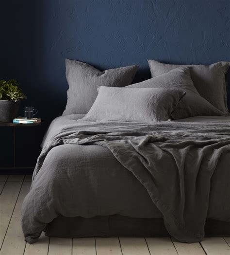 This slate grey bedroom feels bright thanks to a bold combination of a blue upholstered bed, colourful rugs and a pile of statement soft furnishings. Charcoal 100% Linen Bedding | Secret Linen Store