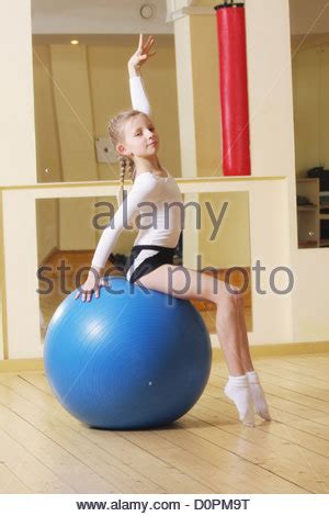 Skinny amateur teen bouncing on big ball. Little girl gymnast posing with blue ball Stock Photo - Alamy