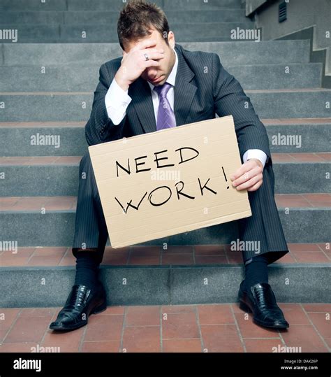 Depressed businessman holding need work sign Stock Photo - Alamy