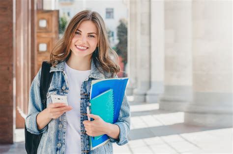 Kollegen zu kollegen (oft) 2. Junge studentin, die gegen universität lächelt. | Premium-Foto